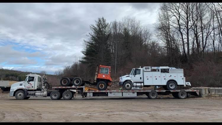 A DCT tractor hauling a damaged service truck and a cut down tractor together on a lowboy trailer.